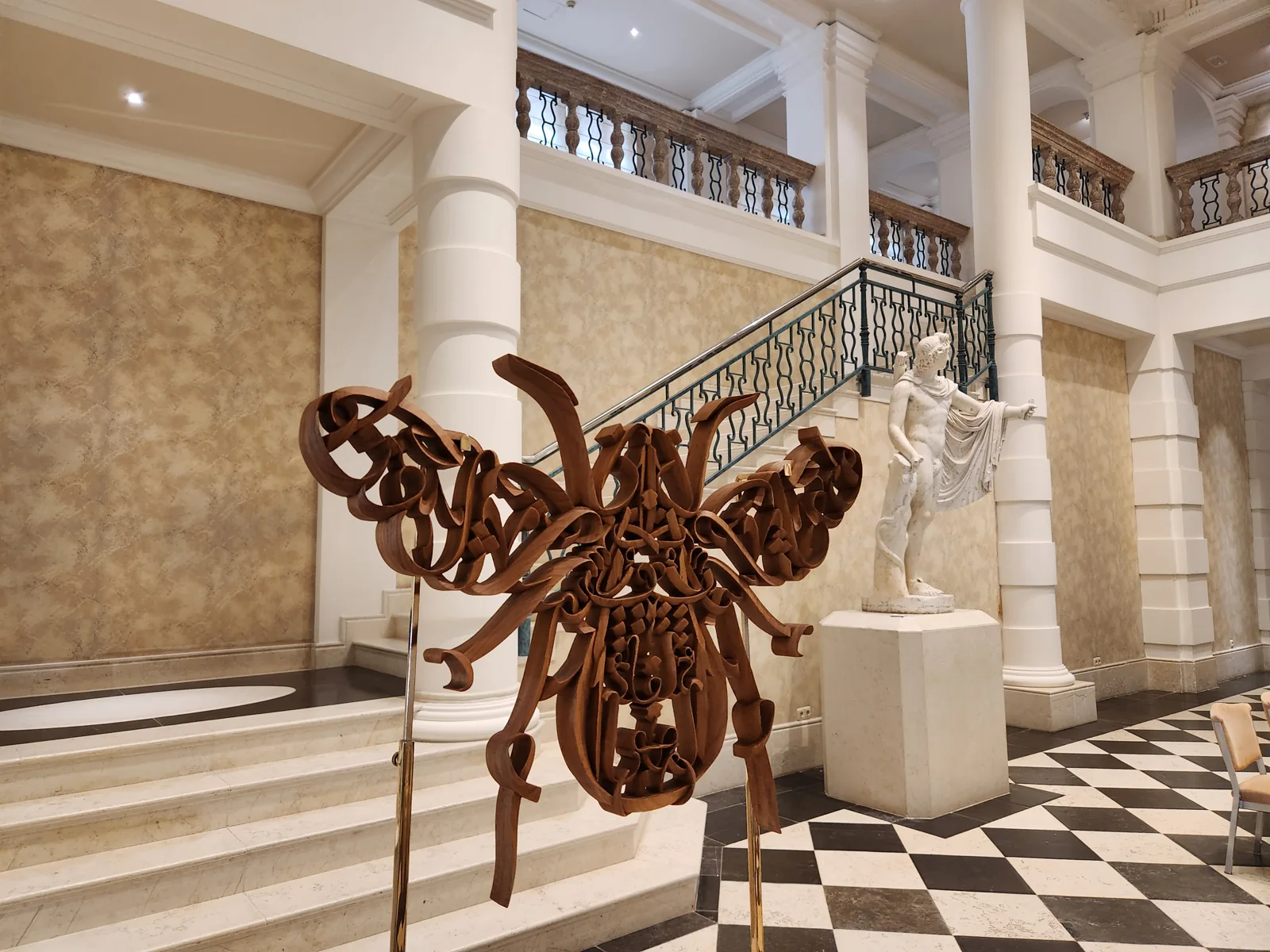A freestanding calligraphic sculpture displayed in a hall with columns